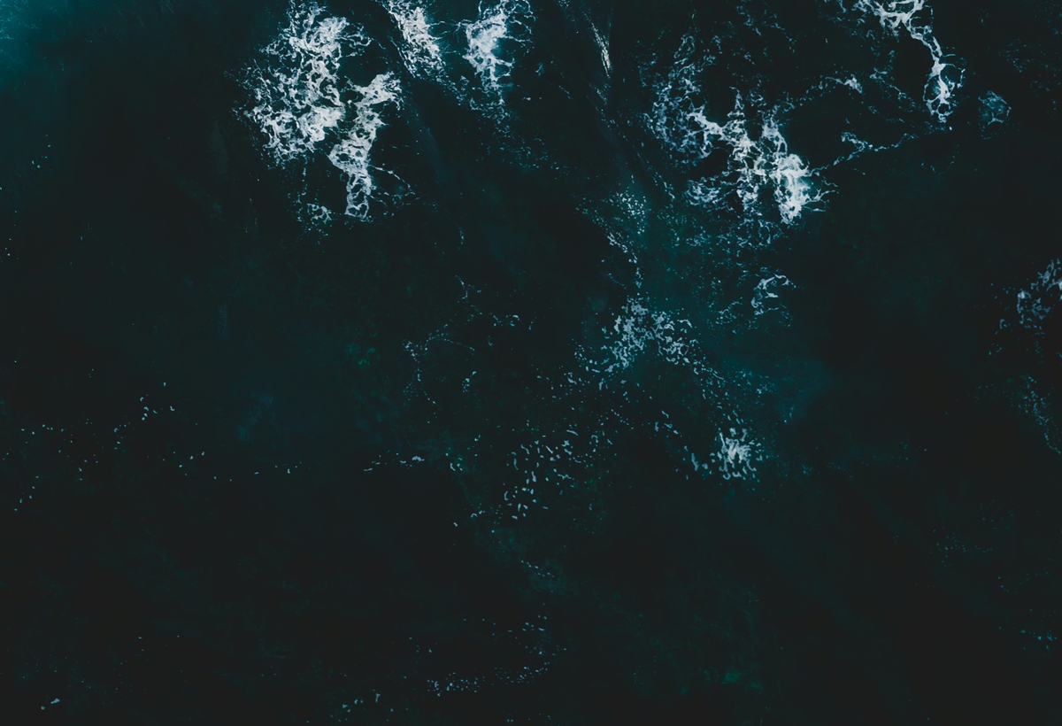 drone shot of dark ocean with breaking waves