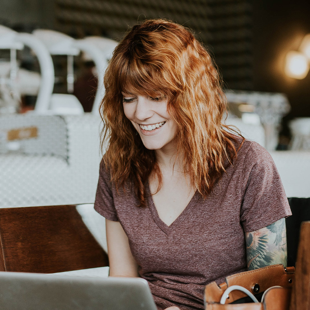 woman smiling while looking at laptop